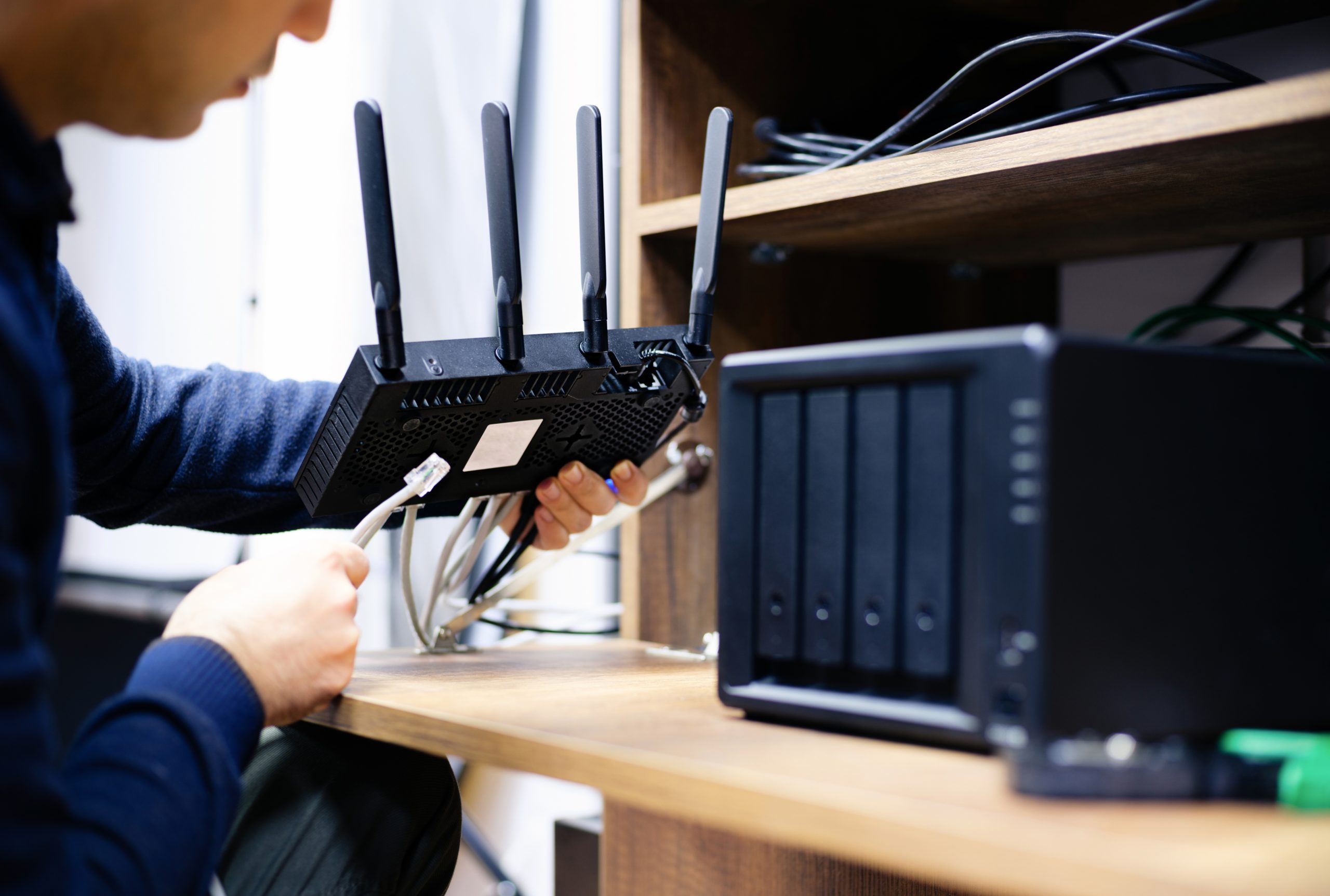 Technician configuring a wireless router and preparing cables for a network-attached storage (NAS) system